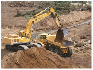Photo of a backhoe filling a dump truck at a construction location.