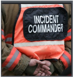 Photo of a responder with his back to the camera wearing a high-visibility safety vest with a patch that reads 'Incident Commander.'