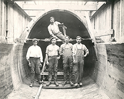 Photo of workmen standing in the end of the arch pipe at the time of its original installation in 1922.