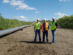 Members of the project team meet on site concerning a utility conduit that sits above grade.
